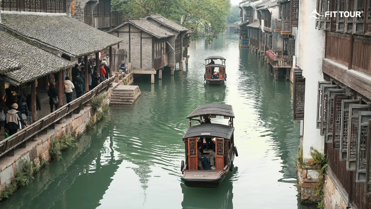 Thuyền gỗ di chuyển trên dòng kênh nhỏ trong khu làng cổ