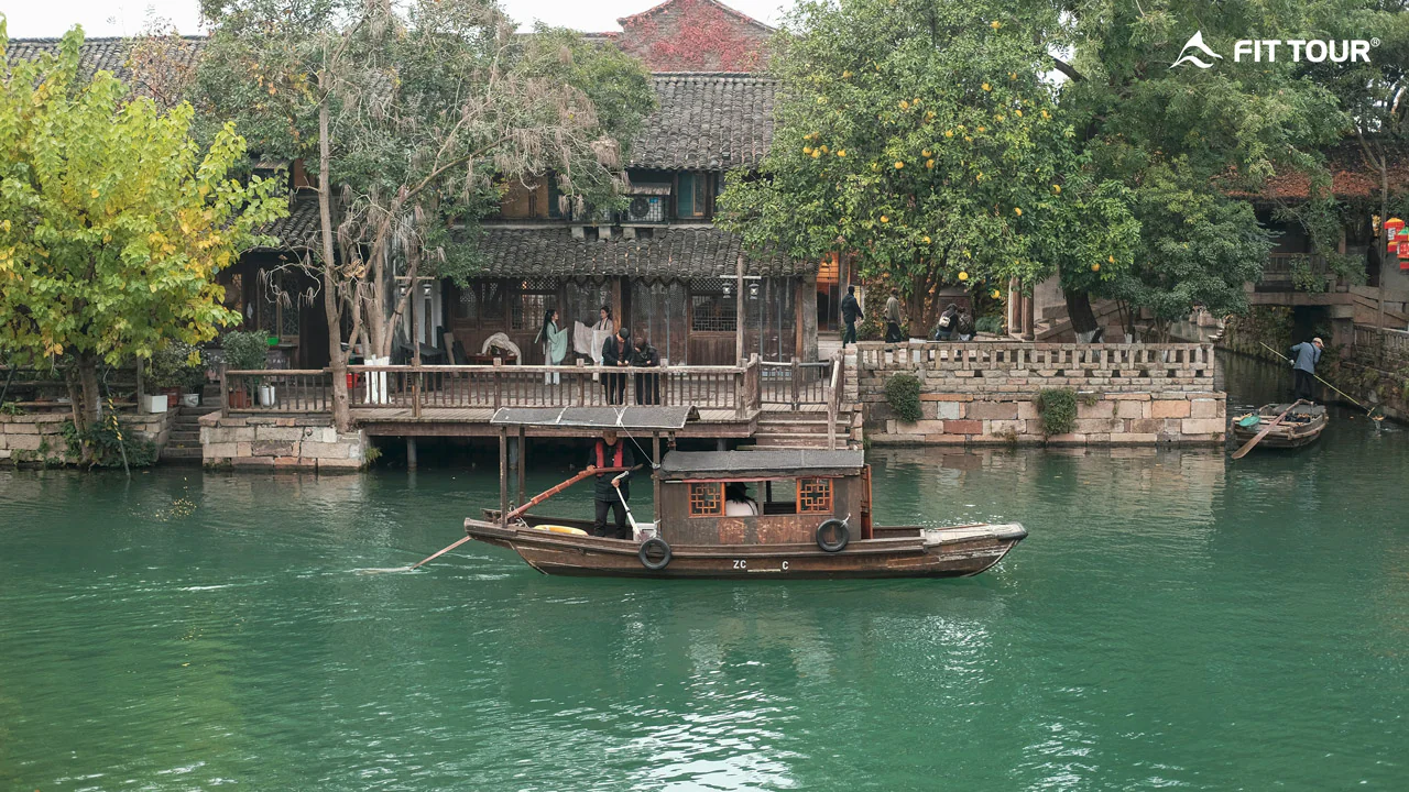 Thuyền gỗ lững lờ trôi bên làng cổ, mang nét đẹp yên bình và thơ mộng