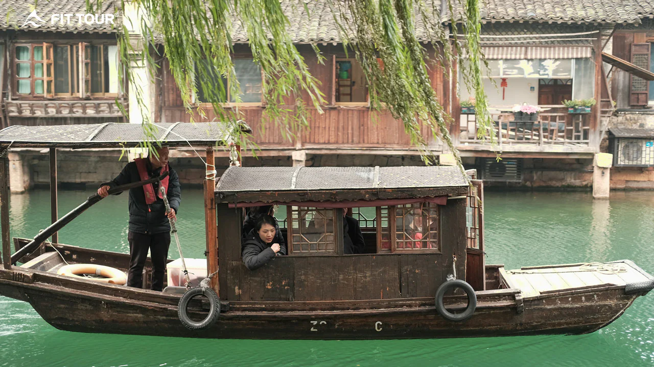 Thuyền gỗ truyền thống chở khách tham quan trên dòng sông xanh ngắt