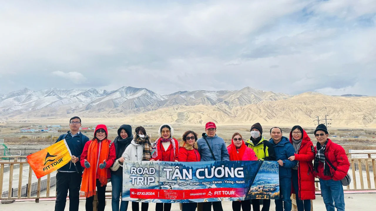 Đoàn khách FIT Tour check-in tại Hồ Bạch Sa, Nam Cương với phông nền núi tuyết và sa mạc hùng vĩ trong hành trình road trip Tân Cương