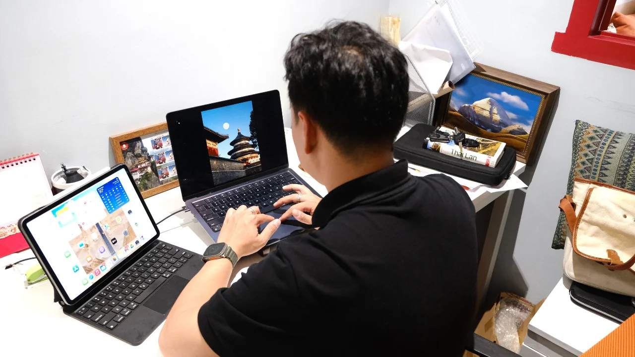 Không gian bàn làm việc cá nhân tại văn phòng FIT TOUR, gợi cảm hứng du lịch với sách ảnh, iPad và laptop